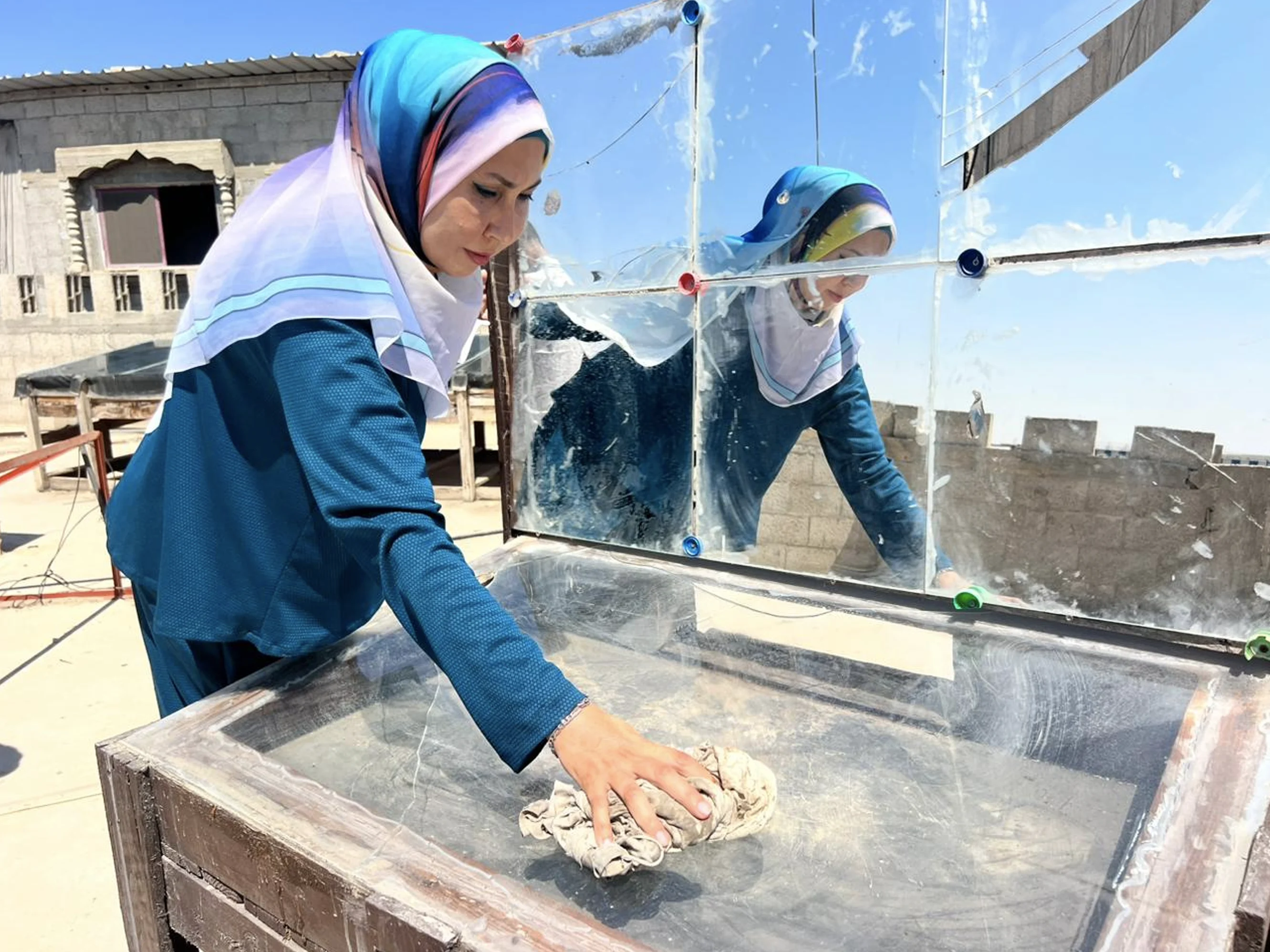 Enas limpia y prepara la superficie reflectante de la cocina solar